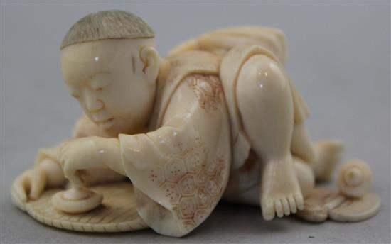 A Japanese carved ivory okimono of a child with a spinning top, 19th century, 17.6cm